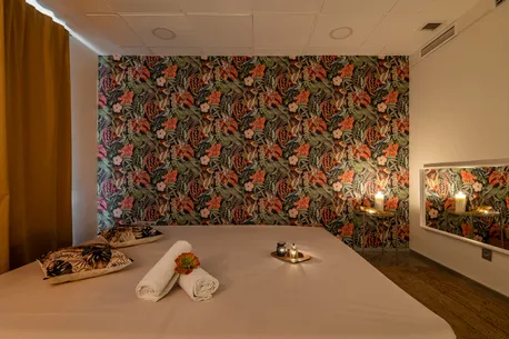 Habitación íntima con cama y pared floral para disfrutar de masajes eróticos en Barcelona