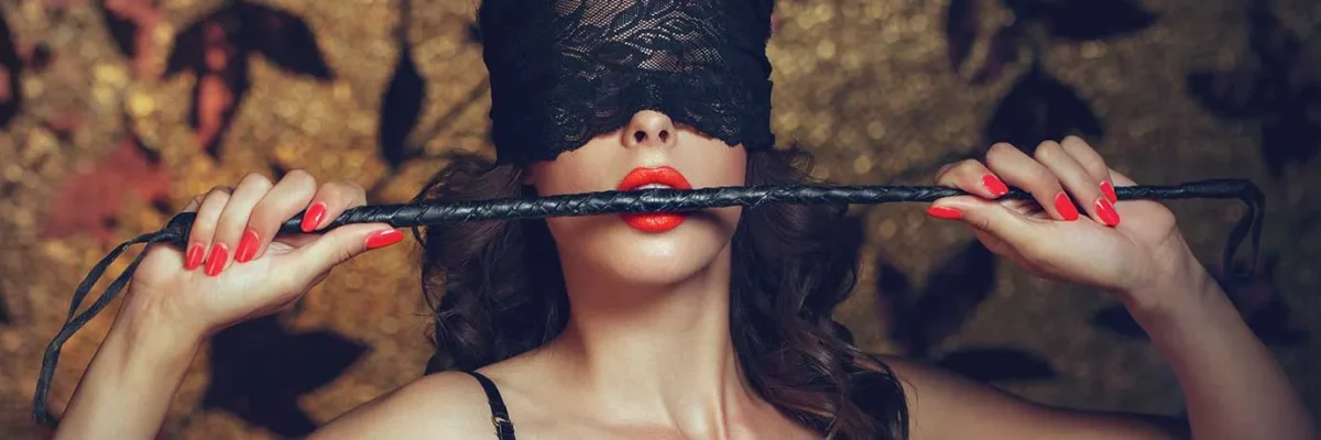 Femme les yeux bandés tenant un fouet, suggérant une exploration sensorielle dans un contexte de massage BDSM.