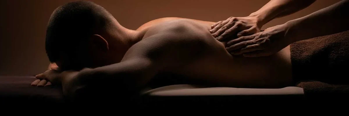 A man receiving a body to body massage in a tranquil and relaxing environment, with emphasis on care and physical connection.
