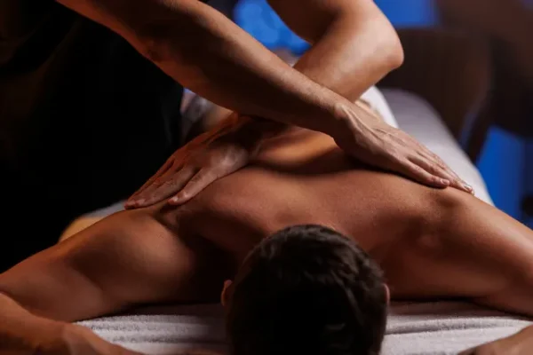Massage gay centré sur le dos d'un homme, dispensé dans une ambiance sereine et professionnelle.