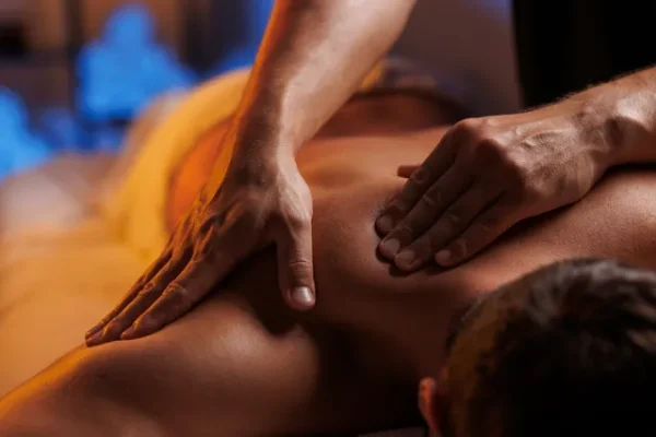 Détail d'un massage gay en cours, mettant l'accent sur la technique et le bien-être du receveur