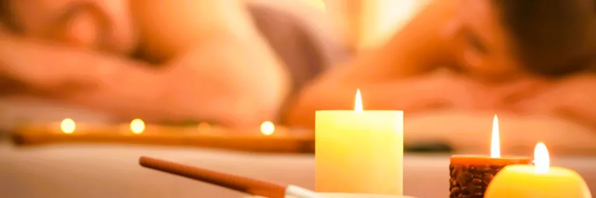 A couple enjoying an erotic massage together, with lit candles creating an intimate atmosphere