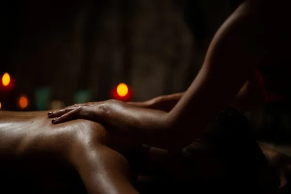 Therapist's hands massaging with oil in a warm and dim environment, symbolizing the indulgent experience of the Supreme massage