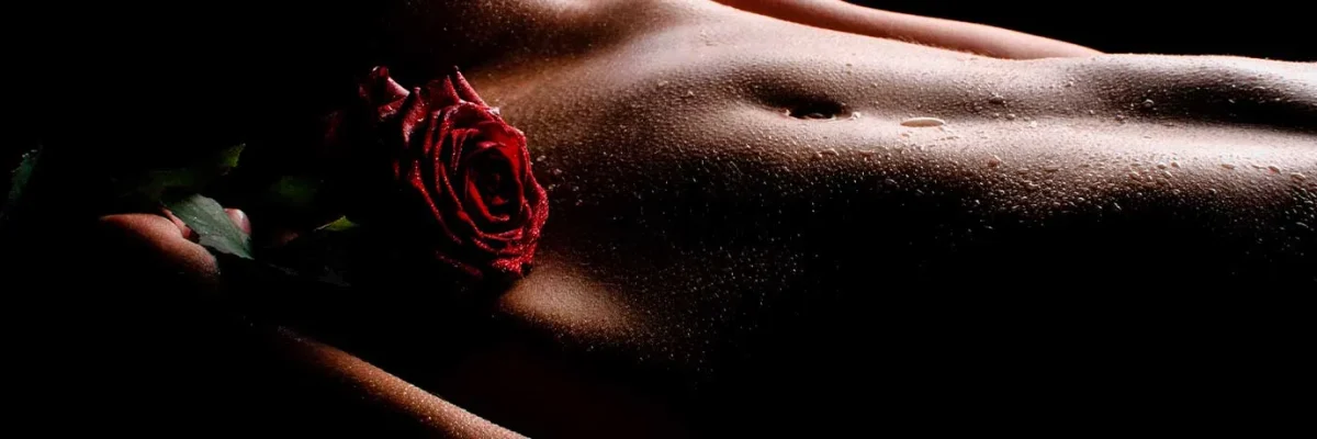Détail artistique d'une rose sur la peau humide, évoquant l'essence et la délicatesse du massage tantra.